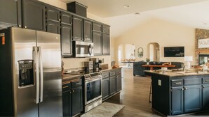 A modern kitchen with dark cabinetry, stainless steel appliances, and a central island.