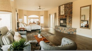 A spacious living room with a fireplace, a large bed, and a cozy seating area.