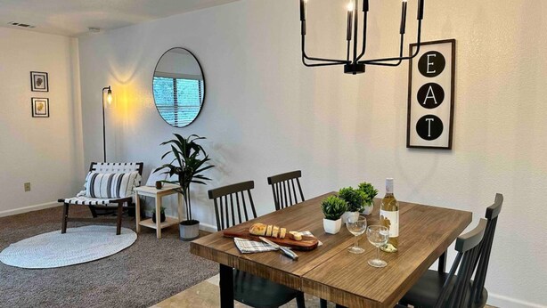A dining area with a wooden table, black chairs, a chandelier, and a wall-mounted sign with letters. - Prime Location Yosemite Expedition by Casa Oso (Oakhurst)
