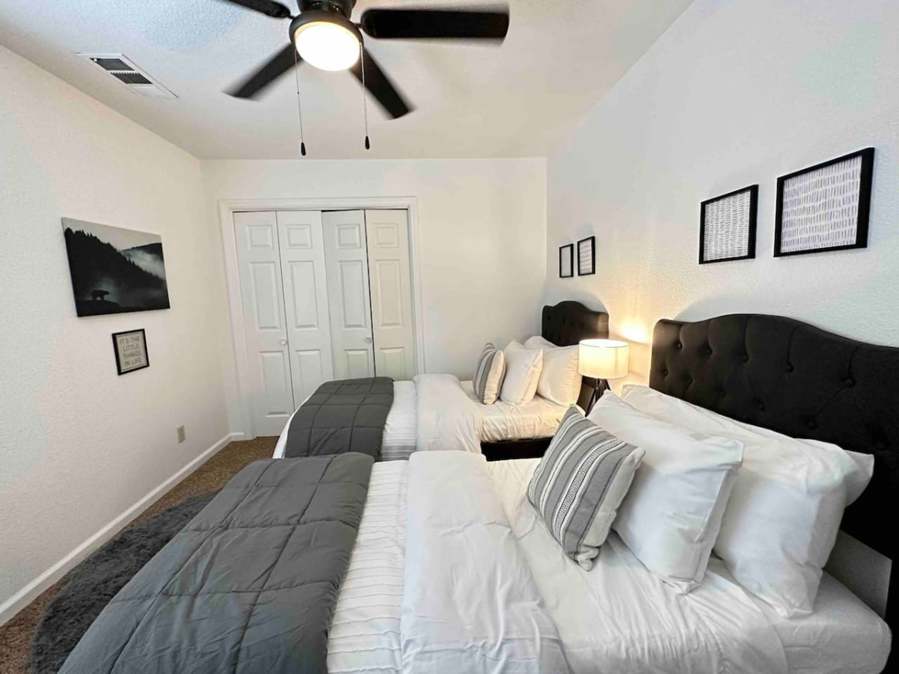 Une chambre avec deux lits, un ventilateur de plafond et une porte.