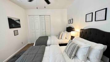 A bedroom with two beds, a ceiling fan, and a door.