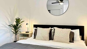 A neatly made bed with a round mirror above it, a bedside lamp, and a potted plant. - Prime Location Yosemite Expedition by Casa Oso (Oakhurst)