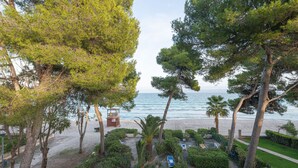 A beachside property with a lifeguard tower, palm trees, and a clear view of the sea. - Casa Ketilla, front line apartment (Alcúdia)