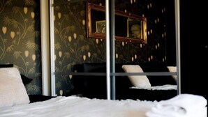 Habitació d'hotel amb llit, un mirall gran i paper pintat amb un disseny.
