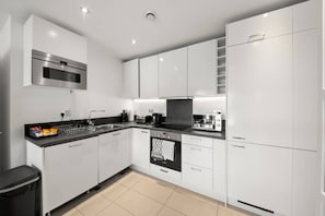 A modern kitchen with white cabinets, a stainless steel oven, a microwave, a toaster, and a dishwasher.