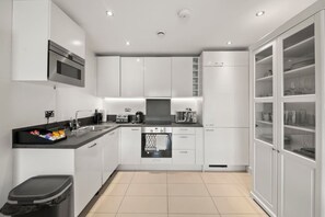 A modern kitchen with white cabinetry, a black countertop, and a built-in oven. - Spacious Retreat for 7 with 2 Bathrooms (Berkshire)