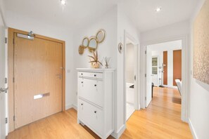 A hallway with wooden flooring, a white cabinet with drawers, and a door with a mirror.