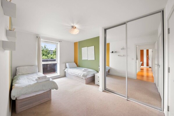 A bedroom with two beds, a sliding glass door, and a view of the outdoors.