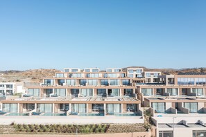 Un hôtel moderne doté de nombreux balcons, d’une piscine et offrant, en toile de fond, un paysage désertique.