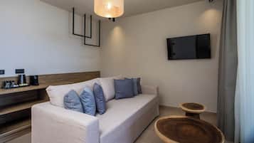 En moderne stue med sofa, sofabord og et vægmonteret fjernsyn.