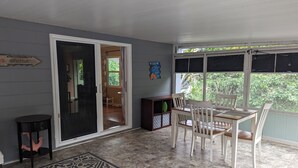 A covered patio area with a dining table and chairs, a small side table, and a decorative rug. - Charming, treetop Indian River Hideaway (Cocoa)