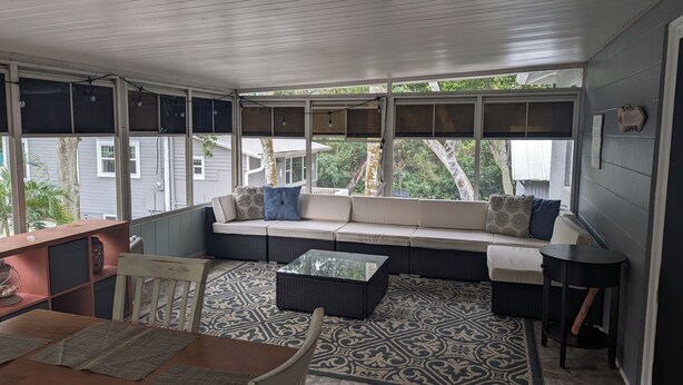 A covered porch with a sofa, a small table, and a chair. - Charming, treetop Indian River Hideaway (Cocoa)