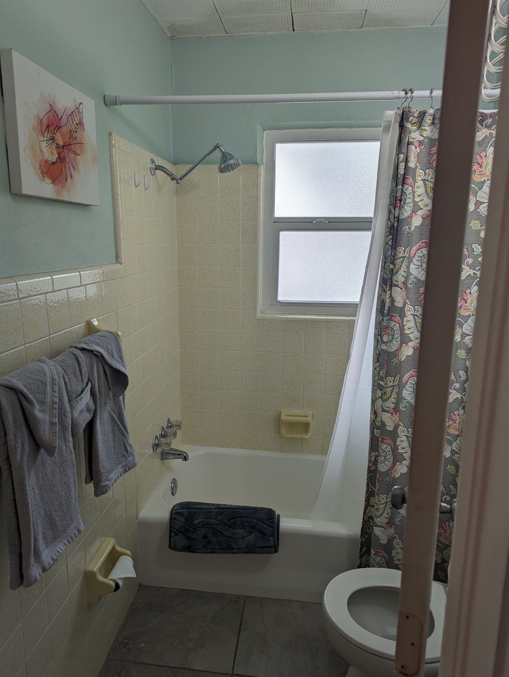 A bathroom with a bathtub, toilet, and a window.