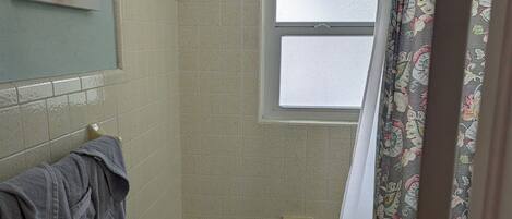 A bathroom with a bathtub, toilet, and a window.