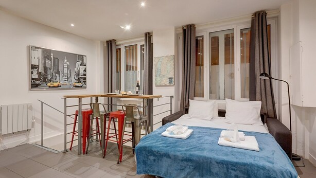 Una habitación de hotel moderna con una cama, un escritorio y dos sillas rojas.