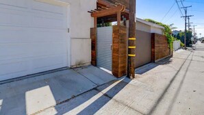 A residential garage with a wooden pergola, a closed garage door, and a sidewalk.
