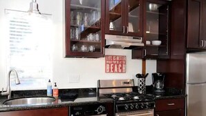 A kitchen with dark wood cabinets, stainless steel appliances, and a 'Life is Better When You're at the Beach' sign.
