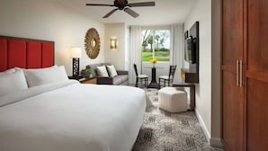A hotel room with a large bed, a ceiling fan, a TV, a dining area with a table and chairs, and a view of a golf course through the window. - Marriott Shadow Ridge Studio Unit- full resort access - Perfect for Coachella (Palm Desert)