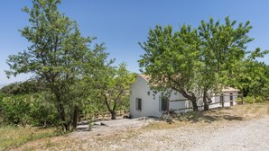 Un edificio blanco con tejado de tejas, rodeado de árboles y un sendero de grava.