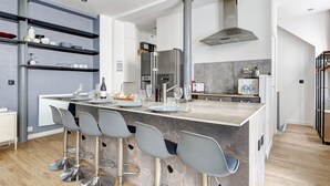 A modern kitchen with a central island, bar stools, and a built-in wine cooler. - TheBlueStay 37 - Cozy Apt in Oberkampf Paris 11 (Paris)