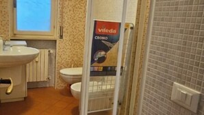 A bathroom with a toilet, sink, and shower area.