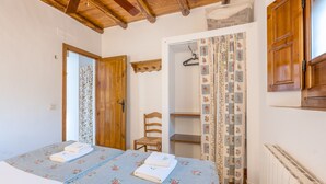 A bedroom with a bed, wooden door, chair, and a radiator.