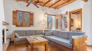 A cozy living room with a checkered sofa, a wooden table, and a ceiling fan.