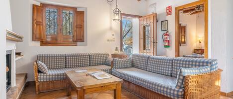 A cozy living room with a checkered sofa, a wooden table, and a ceiling fan.