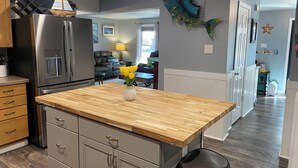A modern kitchen with a wooden countertop, stainless steel appliances, and a decorative fish hanging from the ceiling.