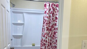 A bathroom with a bathtub, toilet, and shower curtain. - Blue Door at Lake Serene (Lynnwood)