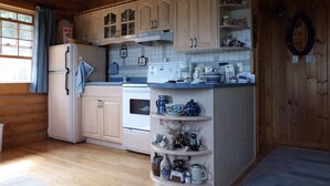 A kitchen with wooden cabinets, a refrigerator, an oven, and a coffee maker. - Cozy log cabin with fantastic views and 2 bathrooms (The Points West Bay)