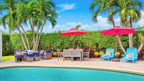 Un espace aménagé au bord de la piscine, comprenant une piscine, des chaises longues et des parasols.