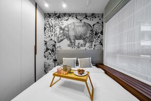 Un dormitorio con una cama grande, una bandeja con productos para el desayuno y un mural en la pared de un rinoceronte.
