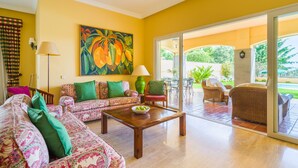 A spacious living room with a patterned sofa, a wooden coffee table, and a large painting on the wall.