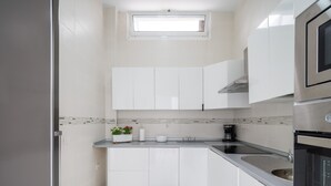 A modern kitchen with white cabinets, a black countertop, a built-in oven, and a window above the sink. - Confital Beach Home  By CanariasGetaway (Las Palmas de Gran Canaria)