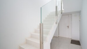 A modern staircase with glass railings and white walls. - Confital Beach Home  By CanariasGetaway (Las Palmas de Gran Canaria)