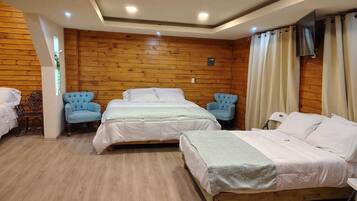 A room with three beds, wooden walls, and a TV on the wall.