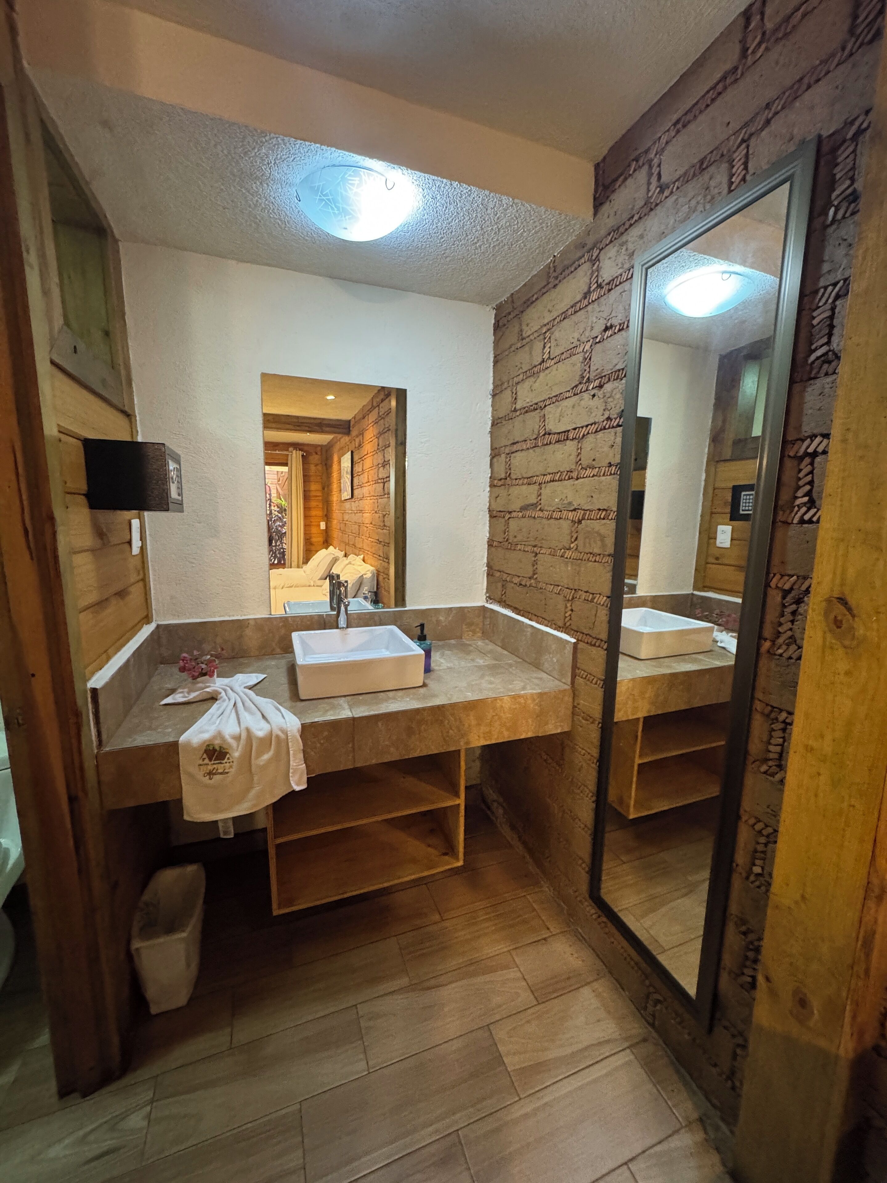 Un baño con tocador de madera, un espejo grande y un lavabo.
