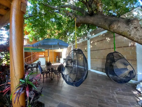 A covered outdoor seating area with hanging chairs, a staircase, and a dining table. - Hotel Cabaña iilldaa, Malinalco (Malinalco)