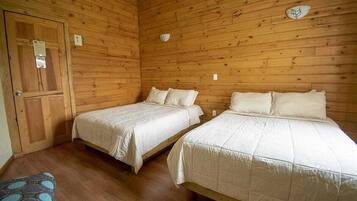 Una habitación tipo cabaña de madera con dos camas, un banco y una puerta.