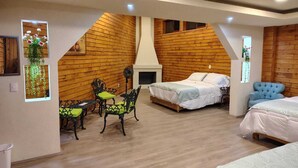 A cozy room with wooden walls, a bed, a sofa, and a dining table with chairs. -  Hotel Cabaña iilldaa, Malinalco (Malinalco)