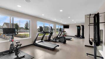 A spacious gym with treadmills, stationary bikes, and a weightlifting area.