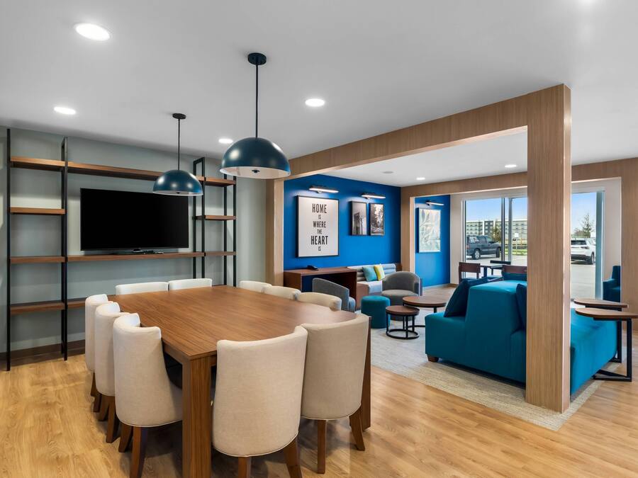 A modern interior with a wooden dining table, chairs, a TV, and a blue accent wall.