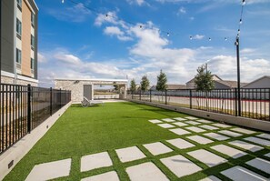 Relax in a serene outdoor space with a lush lawn, stone pathway, and cozy seating area.