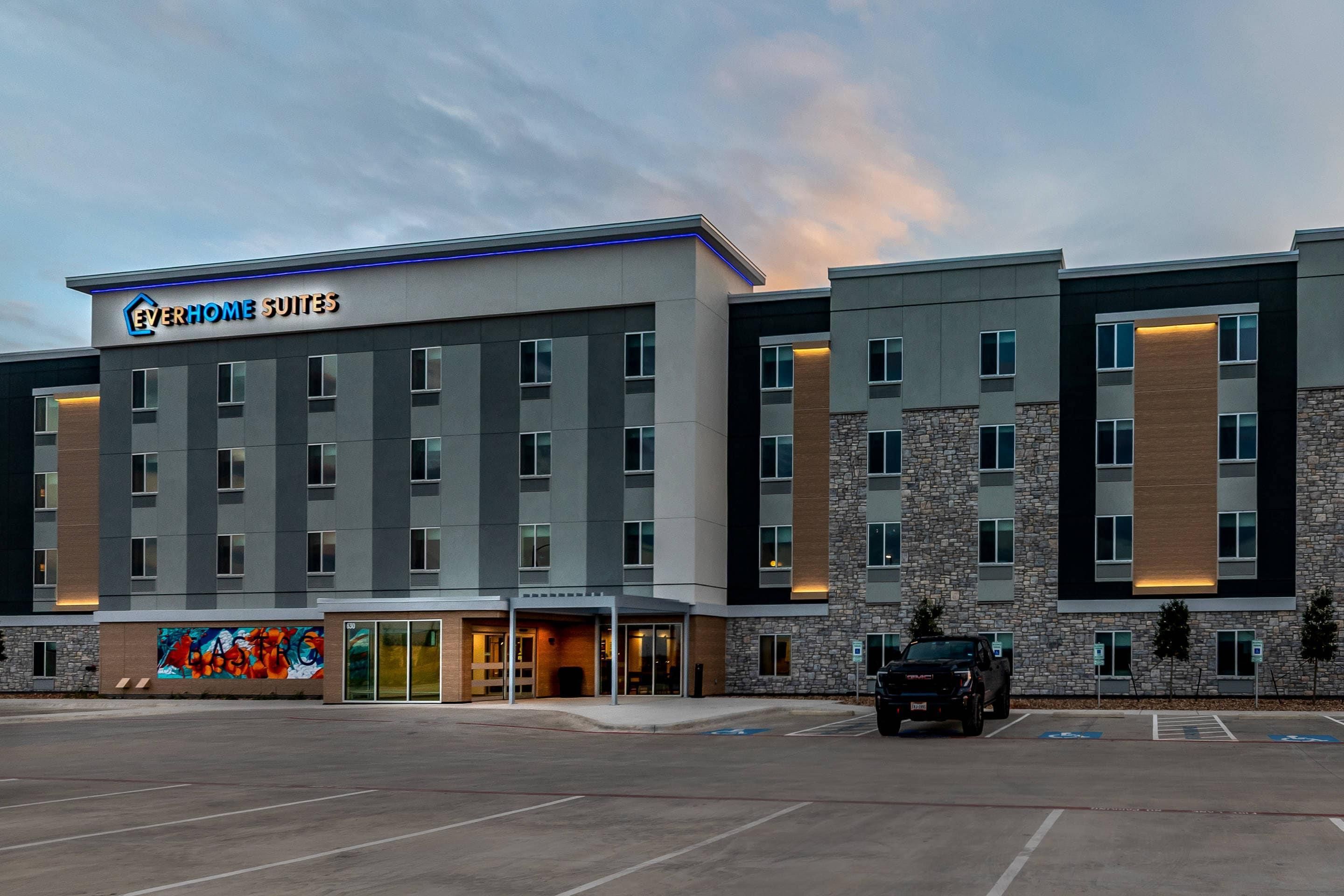 A hotel with multiple floors, a parking lot, and a mural on the side.