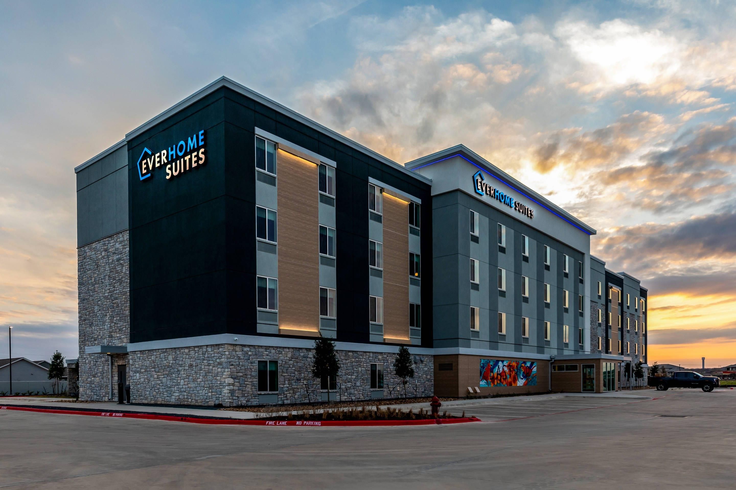 A hotel with a modern design, featuring a stone facade and a flat roof.