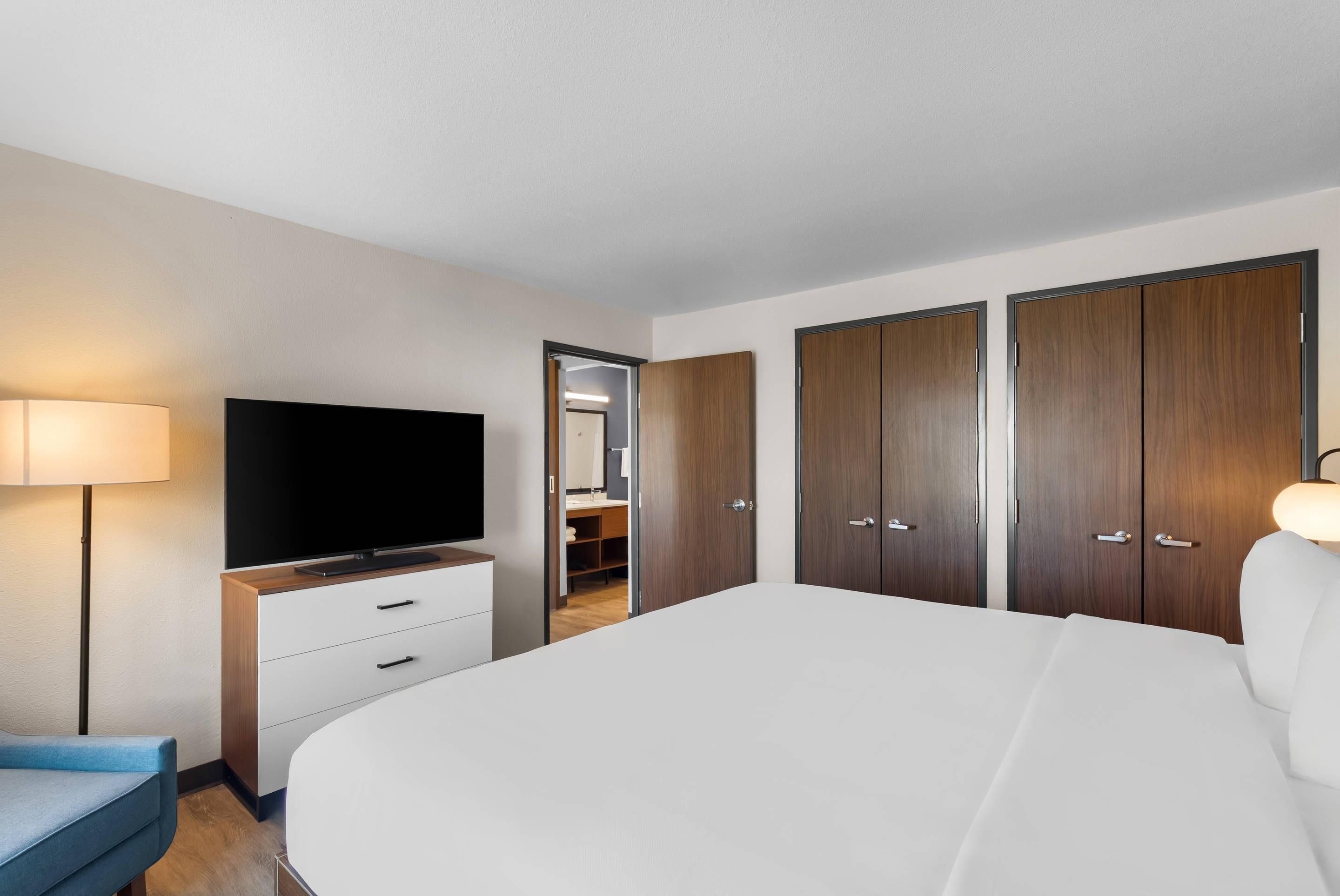 A hotel room with a large bed, a TV, a desk, and a wardrobe.