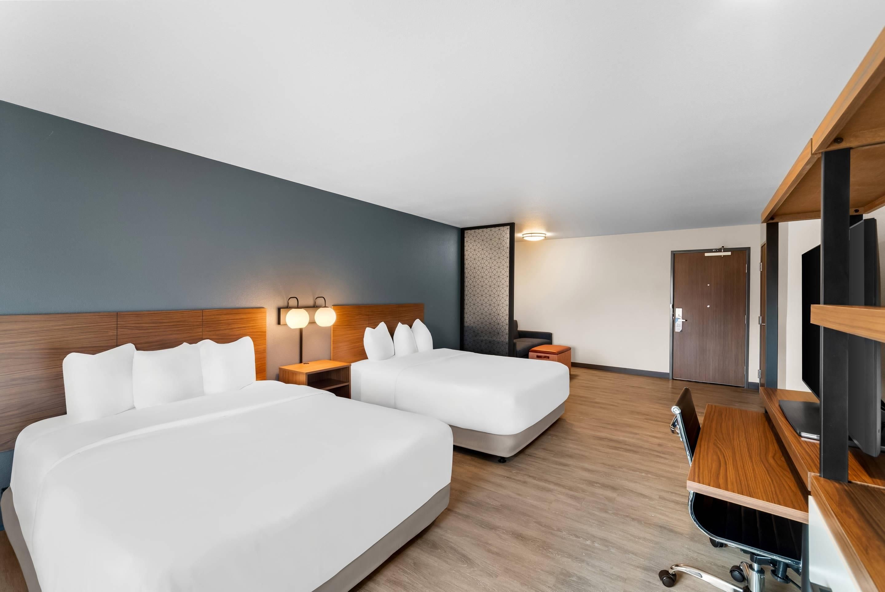 A hotel room with two beds, a desk, a TV, and a wardrobe.