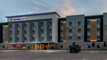 A hotel with multiple floors, a parking lot, and a mural on the side.