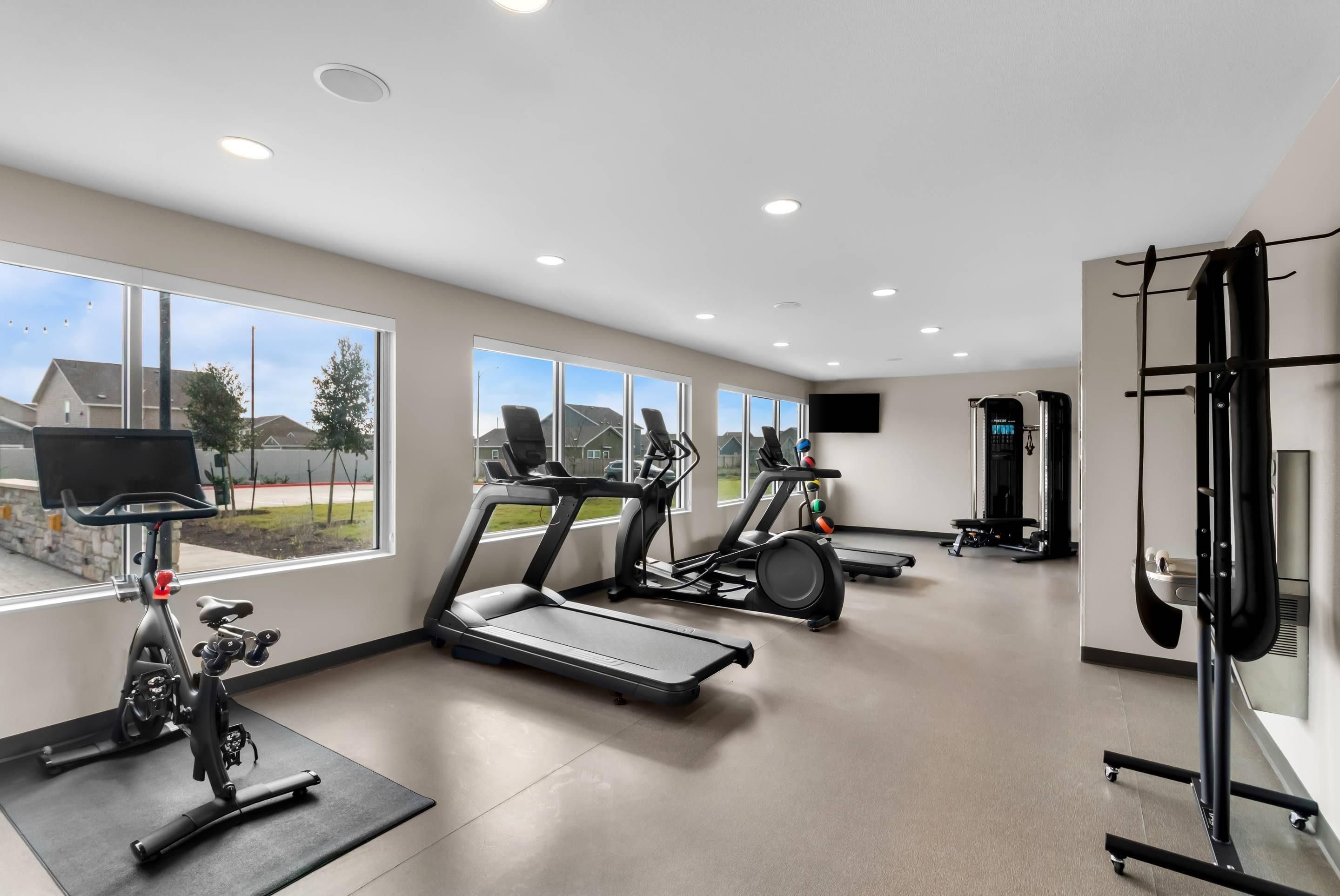 A modern gym with treadmills, stationary bikes, and weightlifting equipment.